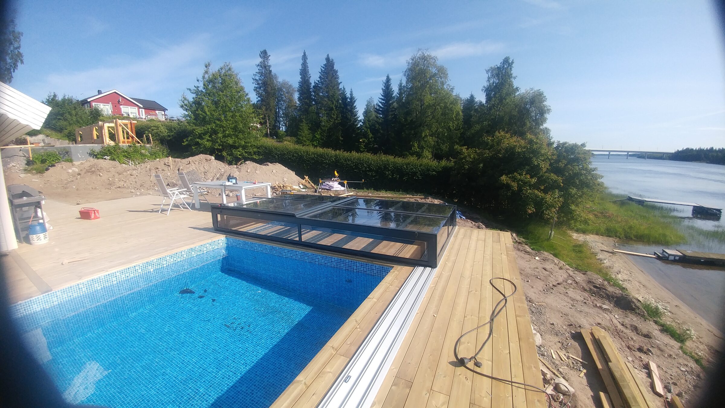 Pool med glasat pooltak i öppet läge en klar sommardag