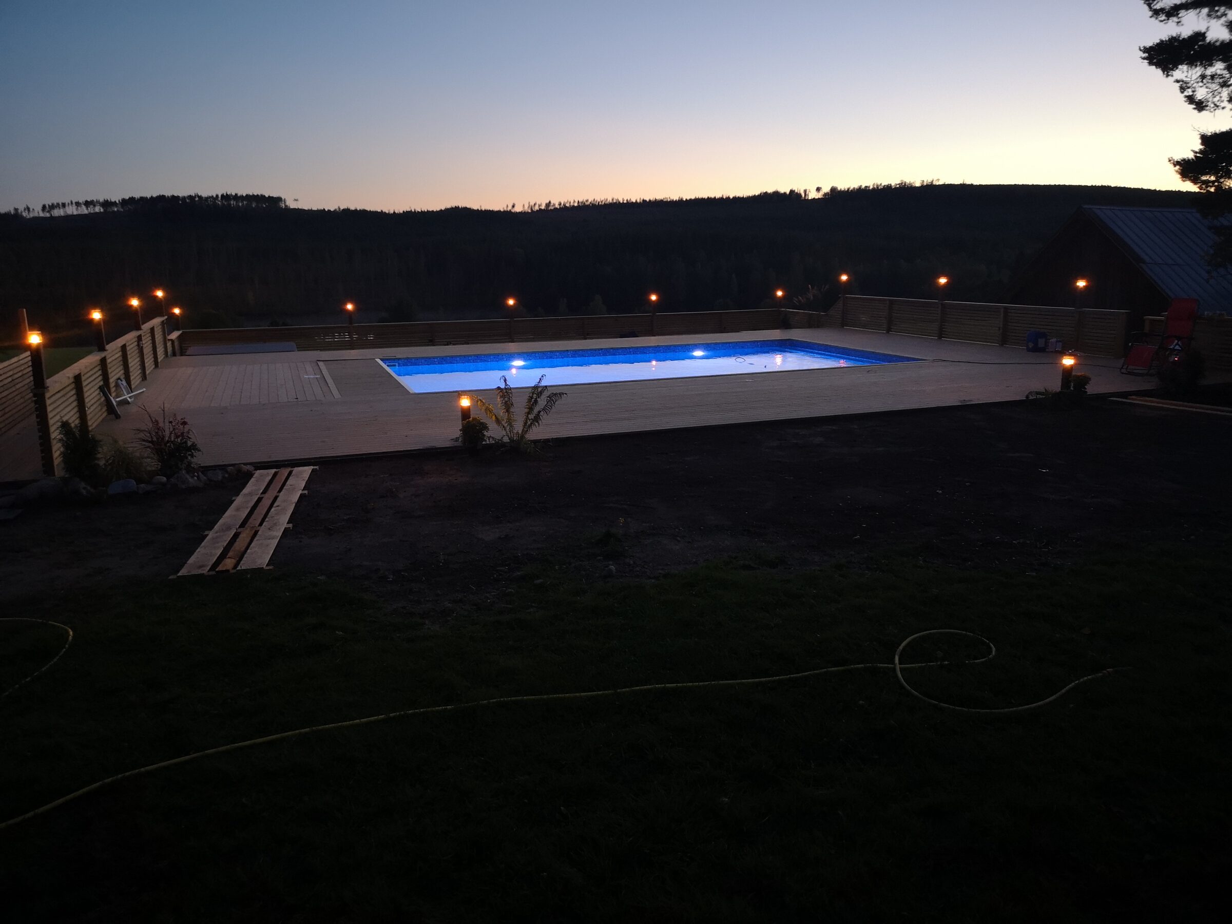 Pool i skymning med varm belysning runt uteplatsen